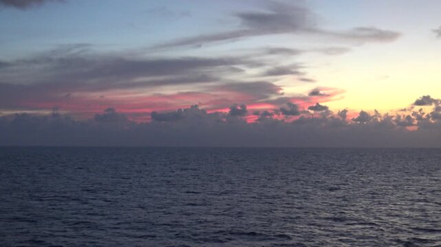 Pinkfarbener Sonnenuntergang &uuml;ber dem offenen Meer mit dramatischen Wolken