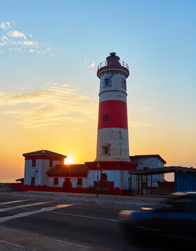 Jamestown lighthouse illuminates the coast, guiding ships during a vibrant sunset