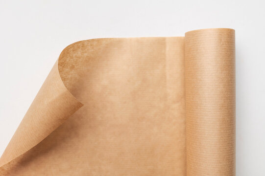 An unrolled roll of baking paper on light gray background, top view. Brown parchment paper for cooking, baking bread or desserts. Space for text and inscriptions