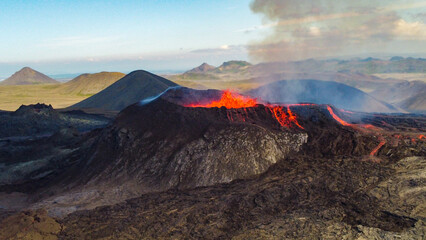Fototapeta premium Aerial view of active Icelandic volcanic eruption with glowing lava and dramatic smoke plumes, YouTube 16x9 format.