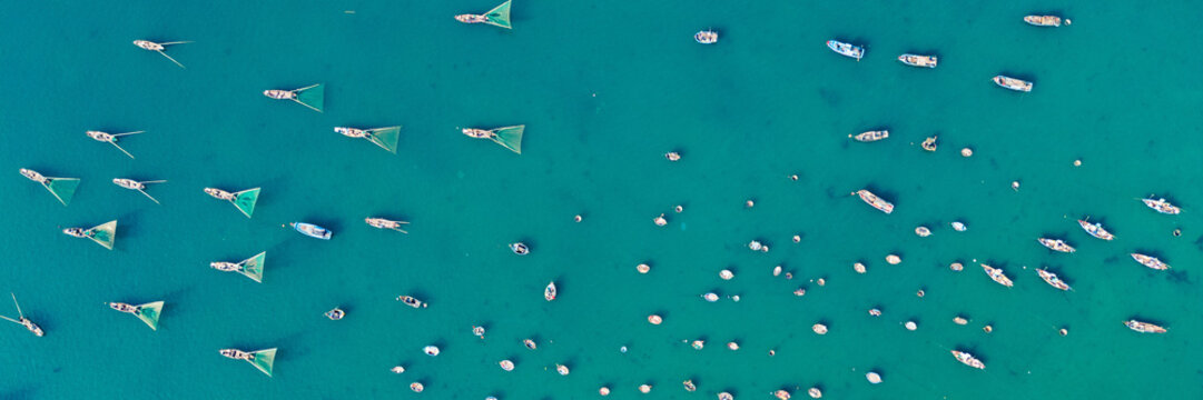 Ultra-wide 3x1 panoramic aerial view of Vietnamese fishing boats on turquoise crystal clear tropical water.