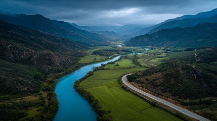 Fototapeta premium Aerial view of blue river winding through green valley and mountains