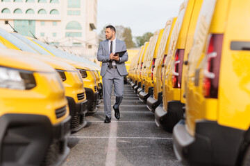 Manager inspecting a fleet of yellow delivery vans © Ljupco Smokovski