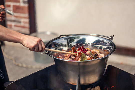 Cooking meat with spices in large outdoor pot