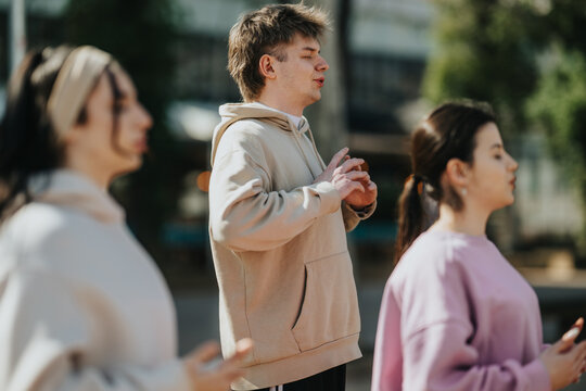 Young people practice mindful breathing and relaxation outdoors in a small group. A calm group meditation scene showing participants focused on breath and presence.
