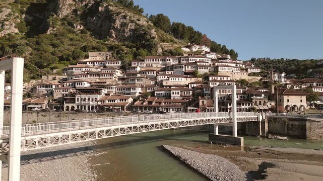 Aerial fly over view Berat - A city of a thousand windows. Gorica Bridge crossing Osum river with Mangalem quarter Ottoman houses hillside UNESCO town Balkan travel destination in Albania