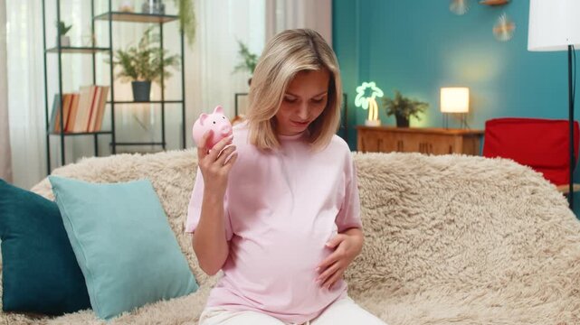 Pregnant middle-aged woman at home shakes empty piggy bank feeling worry checking budget planning future. Caucasian girl on sofa dreams improvement hoping escape poverty saving money with small funds.