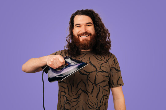 Caucasian Man Holding Iron, Smiling. Studio Portrait With Purple Background, Patterned Shirt And Playful
