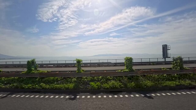 走行中の車窓から見た望む穏やかな海と青空の景色
