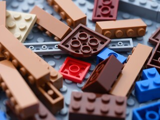 Naklejka premium Tambov, Russian Federation - June 21, 2024 A close-up shot of various colorful Lego blocks scattered on a gray Lego baseplate.