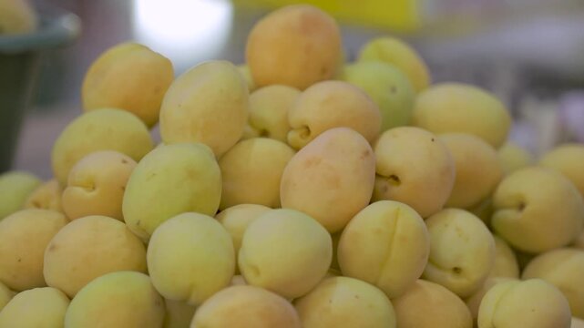 A close-up of fresh apricots displayed at a market, showcasing their vibrant yellow color and natural texture.