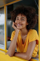 Fototapeta premium Young woman smiling and posing at yellow vehicle window
