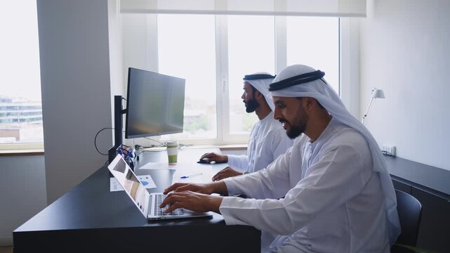 Men with dish dasha working in business office of Dubai. Portraits of successful businessmen in traditional emirates white dress. Concept about middle eastern cultures.