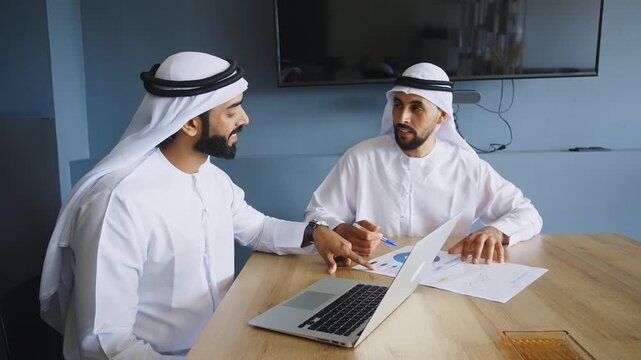 Men with dish dasha working in business office of Dubai. Portraits of successful businessmen in traditional emirates white dress. Concept about middle eastern cultures.