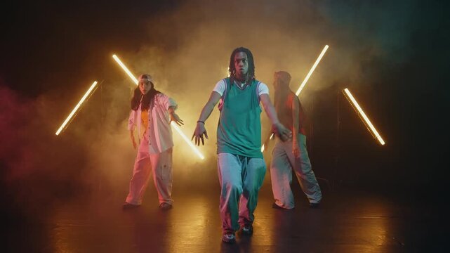 Group of hip hop dancer dancing together in a moody studio with tube neon lights.
