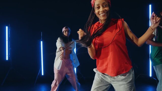Group of hip hop dancer dancing together in a moody studio with tube neon lights.
