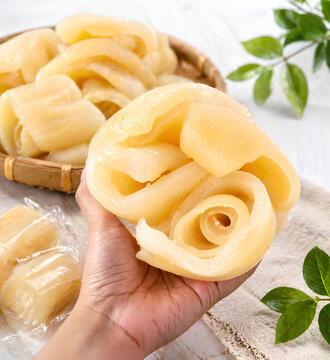 Close-up of Hand Holding Rolled Peeled Cow Skin &ndash; Traditional Asian Food