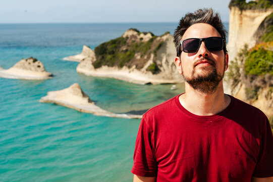 Man Relaxing by Turquoise Sea Cliffs in Corfu, Greece