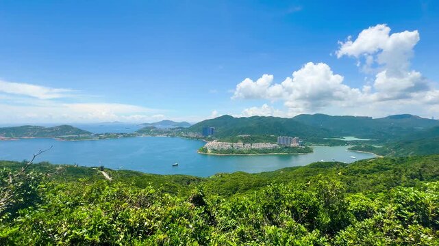 An aerial video shows the lush green island landscape, with buildings and houses along the Dragon's Backbone mountain range in Taiwan. Several boats are visible and gentle waves on a sunny day.