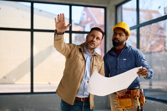 Homeowner and African American construction worker going through blueprints during renovation process.
