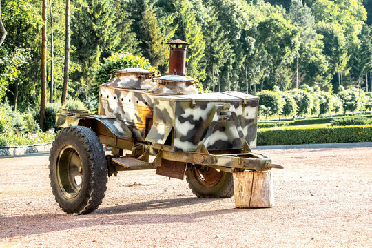 Vintage military field kitchen on wheels with camouflage painting and rusty chimney &mdash; open-air military equipment exhibit