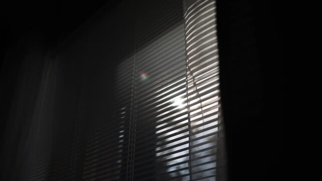 Window blinds slowly closing with sunlight fading and shadows shifting on wall horizontal minimal interior scene natural light transition calm home atmosphere