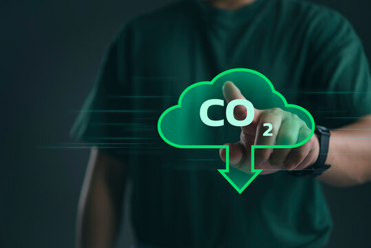Hand pressing digital cloud icon with CO2 text and downward arrow, representing carbon emission reduction, sustainable data systems, climate tech, net zero strategy, eco innovation.