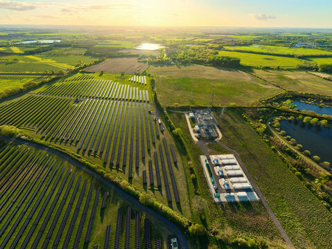Aerial view of Tiln Photovoltaic Solar Farm and Battery Energy Storage System with rows of solar panels and green fields at sunset Retford, England, United Kingdom.