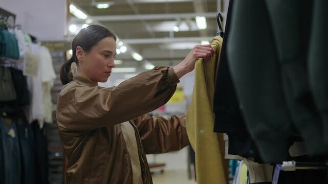 Woman choosing a new hoodie from a clothing rack in a department store