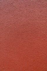 Fototapeta premium Red textured wall surface with rough stucco finish, abstract background for design, construction, and copy space