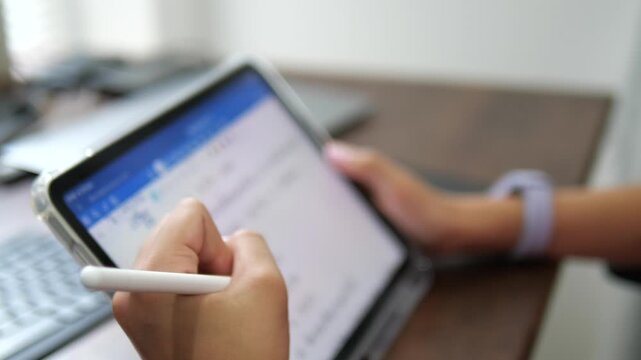 close-up of a child's hand with colorful nail art using a stylus pen to draw and write on a digital tablet screen, creative education and digital art concept