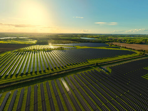 Aerial view of Tiln Photovoltaic Solar Farm and Battery Energy Storage System with rows of solar panels reflecting the golden sun across green rural fields Retford, England, United Kingdom.