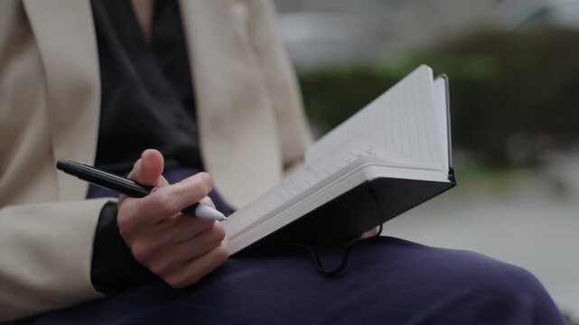Close Up of a Woman Writing Notes in a Notebook Outdoors