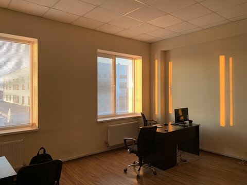A serene office space bathed in warm sunlight, featuring a minimalistic desk and modern design elements.