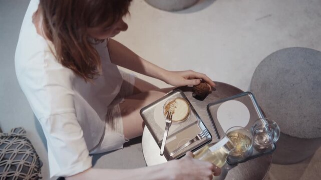 Woman pouring tea while having dessert in modern cafe