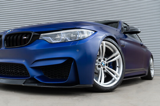 Blue BMW M4 front view low angle, Luxury sporttscar headlight and wheel closeup
