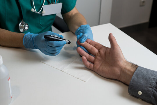 Close-up shot of a small drop of blood on a patient's fingertip after being pricked by a medical professional.