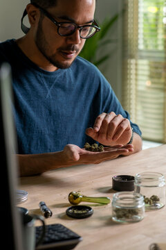 Man choosing cannabis buds, with cannabis equipment and accessories on the table