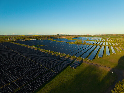 Aerial view of the Tiln Photovoltaic Solar Farm and Battery Energy Storage System with rows of panels across green fields under a clear sky in Retford, England, United Kingdom.