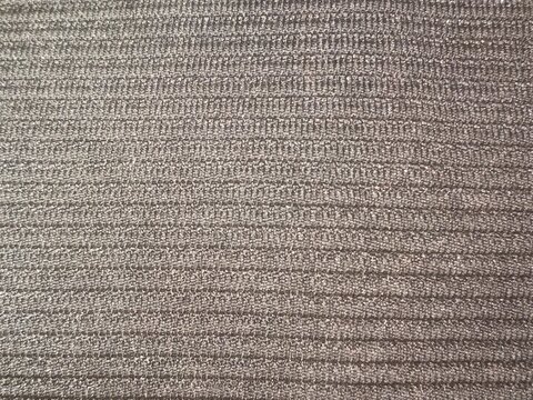 Detailed macro texture of brown ribbed corduroy fabric with parallel horizontal lines and fine textile weave pattern