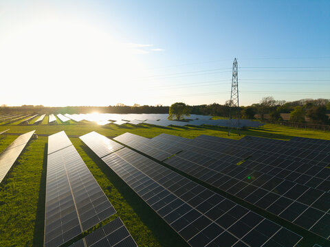 Aerial view of Tiln Photovoltaic Solar Farm and Battery Energy Storage System with rows of solar panels and an electricity pylon in Retford, England, United Kingdom.