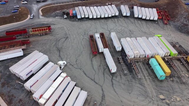 Cinematic drone aerial view at sunset of a modern logistics park in Halifax, Nova Scotia, Canada. Warehouse with many cargo trucks and trailers docked at ramps for goods loading and unloading 4K.