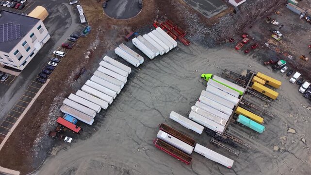 Aerial view at sunset large logistics park and goods warehouse in Halifax, Nova Scotia, Canada. Multiple semi-trucks with trailers parked at loading ramps for cargo loading and unloading operations 
