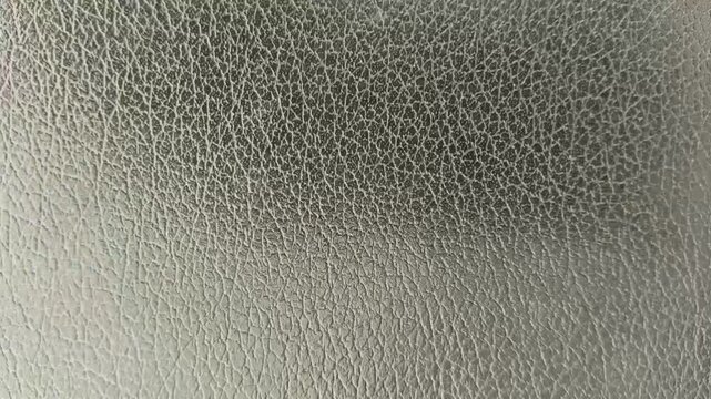 Old and used dark or black color artificial leather surface with wrinkled pattern background texture. Stop motion animation loop. Closeup macro top view.