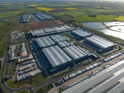 Aerial view of the Iport Avenue logistics hub with large modern warehouses and rows of parked trucks surrounded by green fields in Loversall, England, United Kingdom.