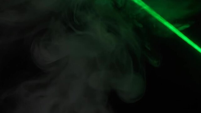 Bright Green Laser Beam Cutting Through Dense Smoke in a Dark Environment.