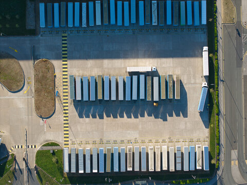 Aerial view of rows of semi-trailers parked at a logistics hub on Iport Avenue with long shadows on the concrete pavement in Loversall, England, United Kingdom.
