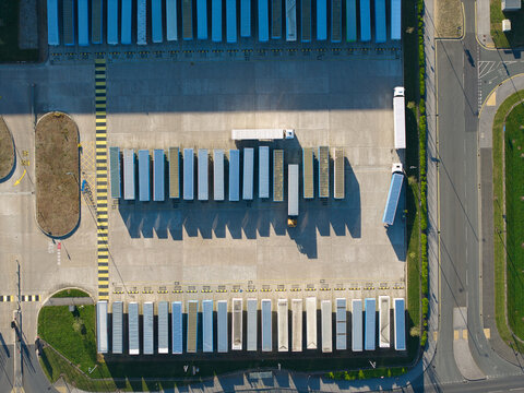 Aerial view of Iport Avenue logistics hub with rows of parked semi-trailers casting long shadows on the pavement in Loversall, England, United Kingdom.