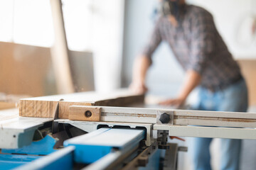 Fototapeta premium Carpenter cutting wood with a table saw in workshop