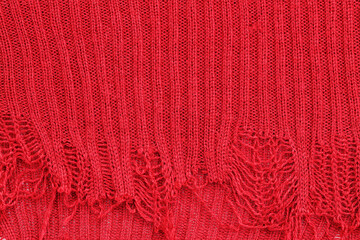 Obraz premium Texture of red knit fabric with loose threads and frayed edges showing design and structure in close-up view